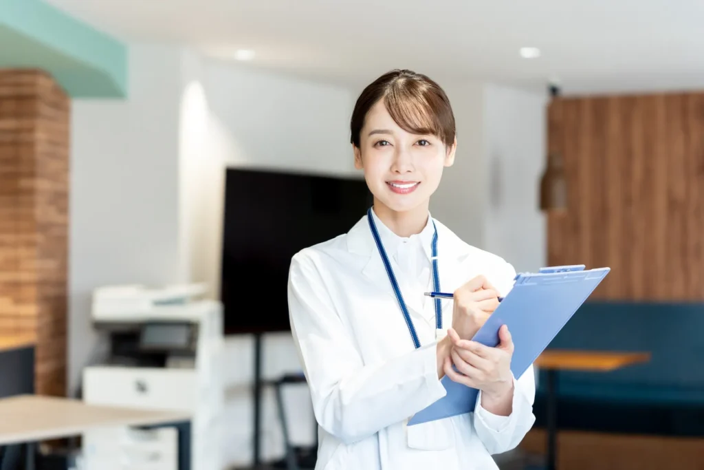 病院・クリニックの女性スタッフがバインダーを持って微笑んでいます。自動精算機選び方のポイントのイメージ